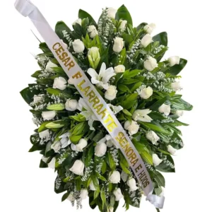Corona fúnebre de rosas blancas y lirios para condolencias con cinta personalizada en Cali